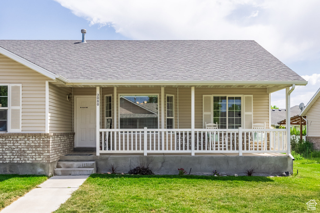Bungalow with covered porch, a shingled roof, and a front lawn