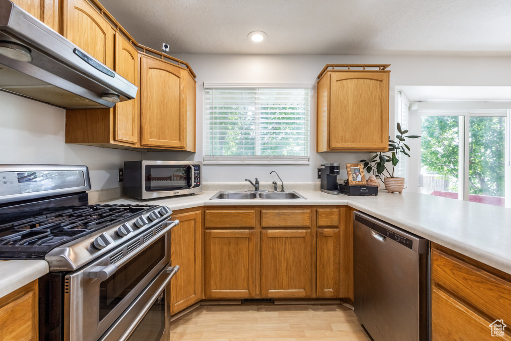 Kitchen featuring stainless steel appliances, ventilation hood, plenty of natural light, light countertops, and recessed lighting