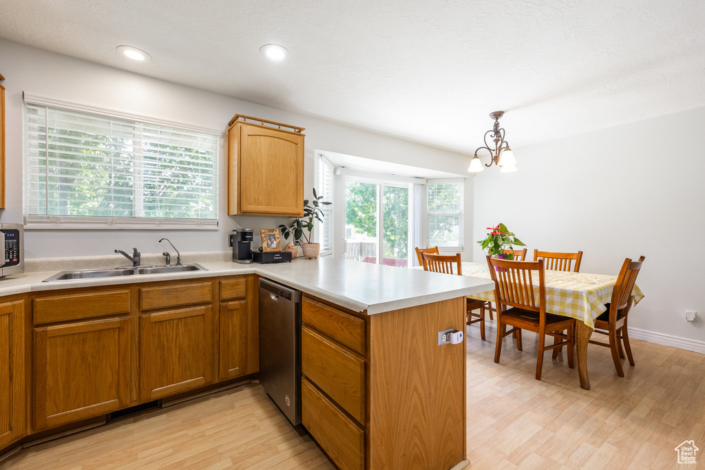 Kitchen featuring dishwasher, a peninsula, light wood-style flooring, a chandelier, and light countertops