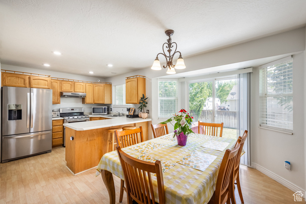 Dining area with light wood finished floors, plenty of natural light, recessed lighting, and a chandelier
