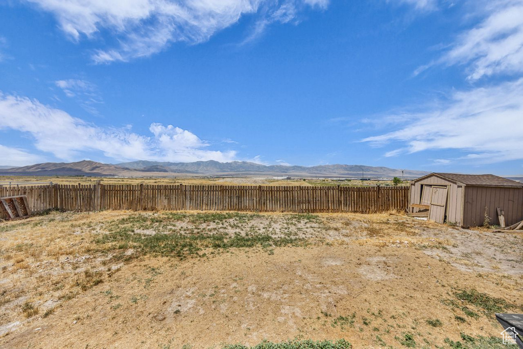 Fenced backyard featuring a shed and a mountain view