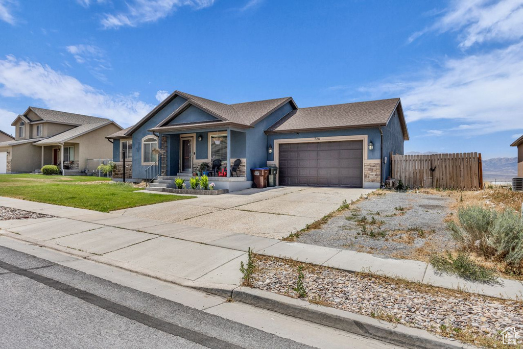 Ranch-style house with an attached garage, concrete driveway, covered porch, stucco siding, and stone siding