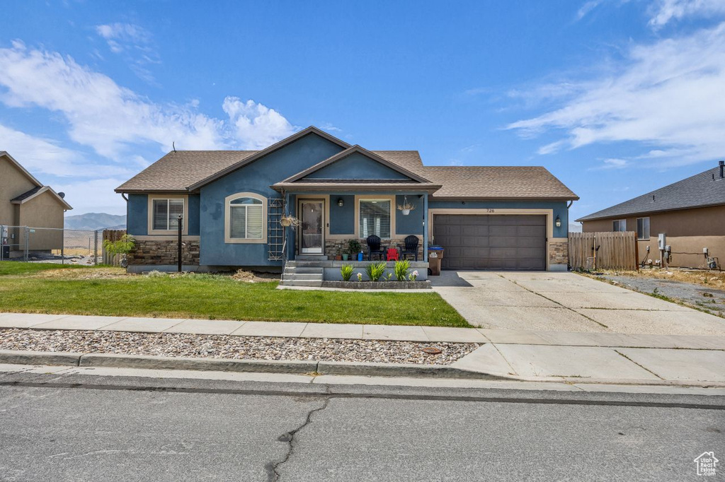 View of front of property with stucco siding, a garage, driveway, and covered porch