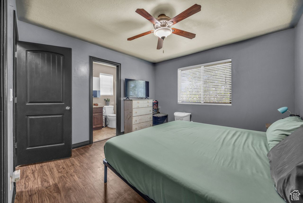 Bedroom featuring wood finished floors, ensuite bath, and ceiling fan