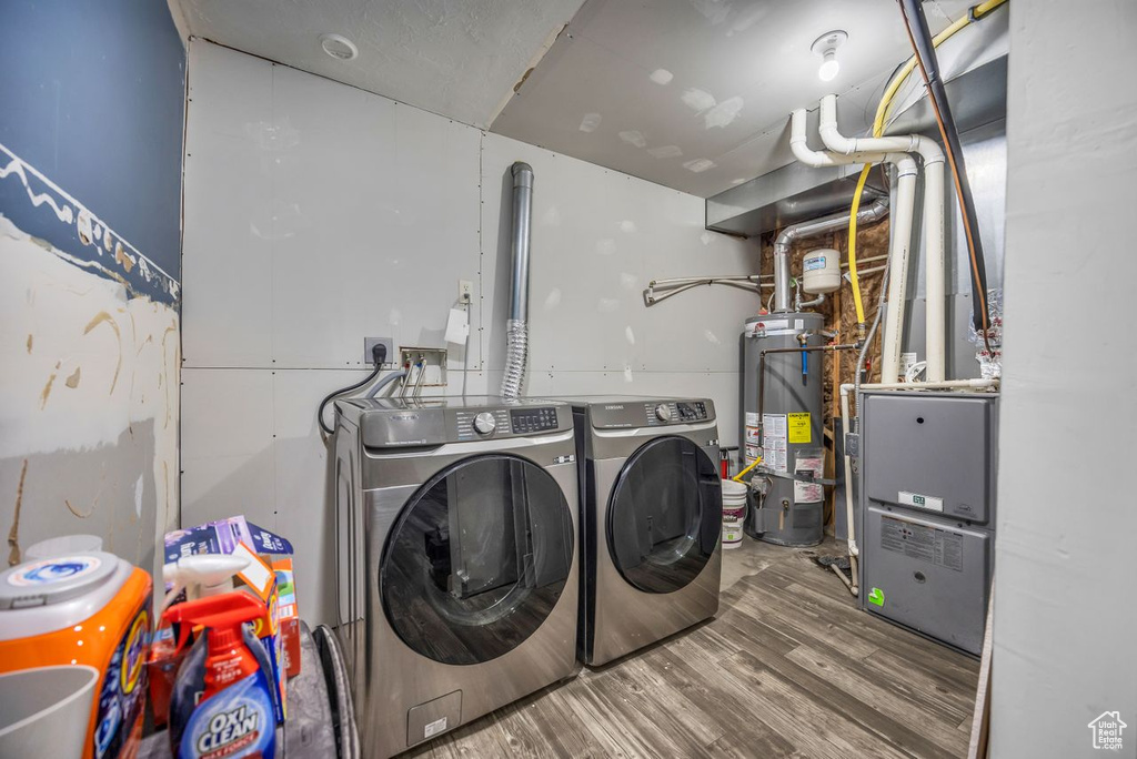 Laundry room with gas water heater, washing machine and clothes dryer, and wood finished floors