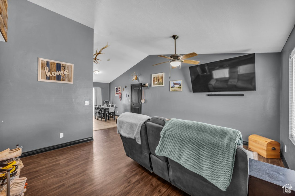 Living room with a ceiling fan, lofted ceiling, and dark wood-type flooring