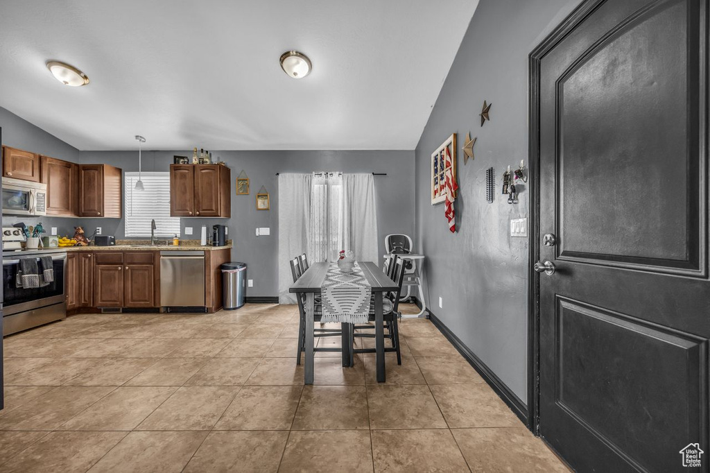 Kitchen with stainless steel appliances, lofted ceiling, light countertops, light tile patterned floors, and pendant lighting