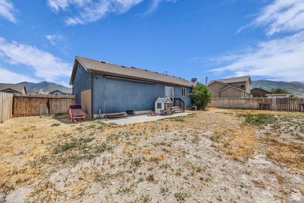 Rear view of house with a fenced backyard and a mountain view
