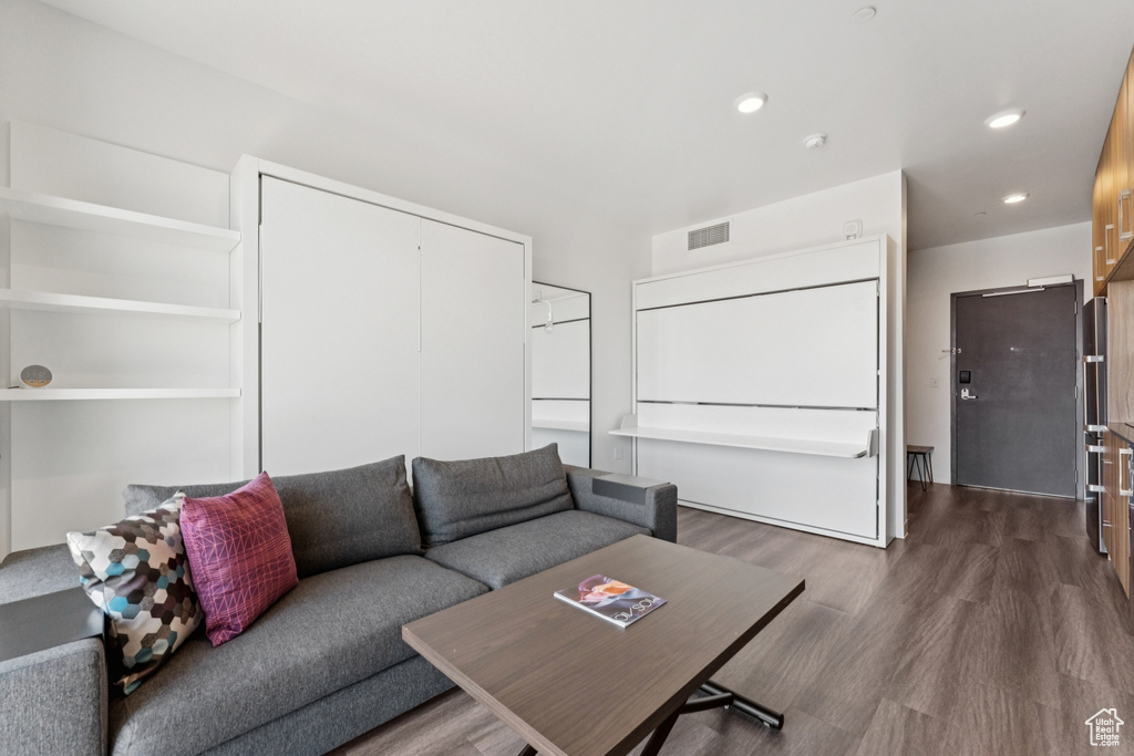 Living area with dark wood-type flooring and recessed lighting