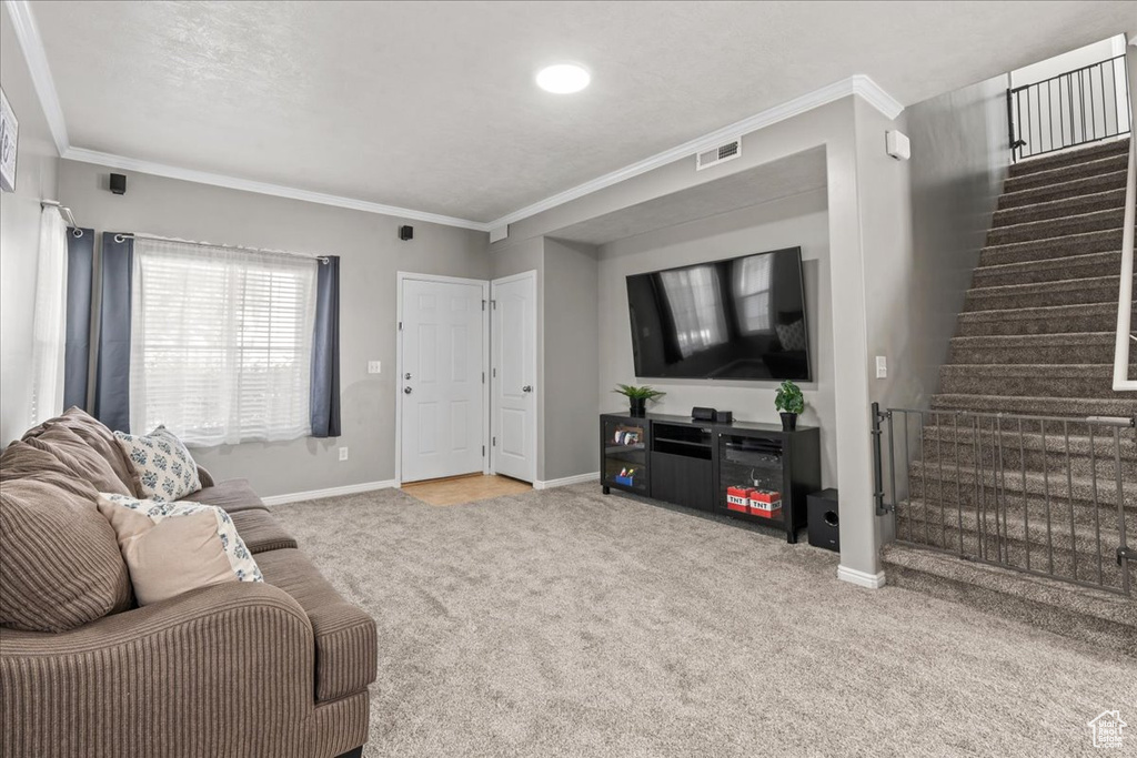 Carpeted living area featuring stairs and crown molding