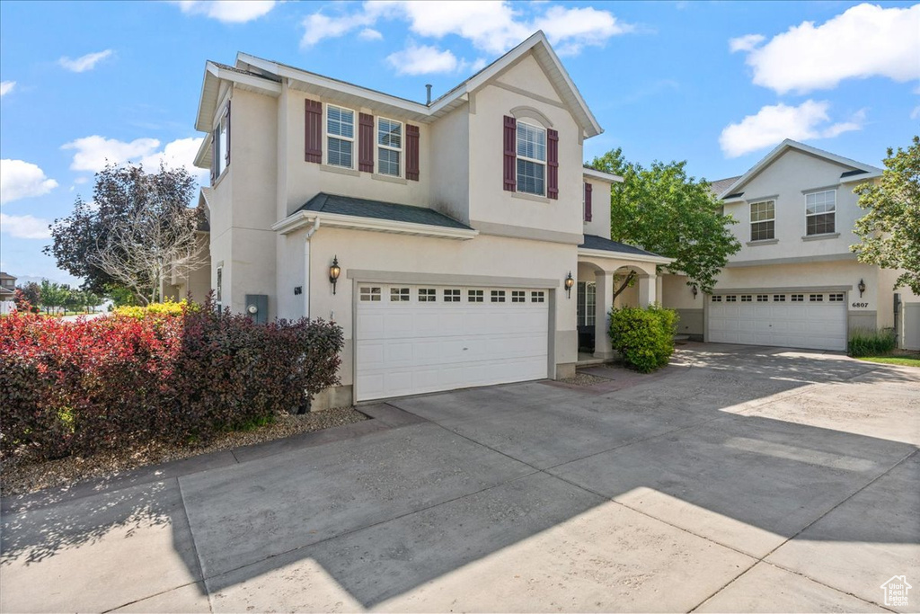 Traditional-style house featuring a garage, stucco siding, and driveway