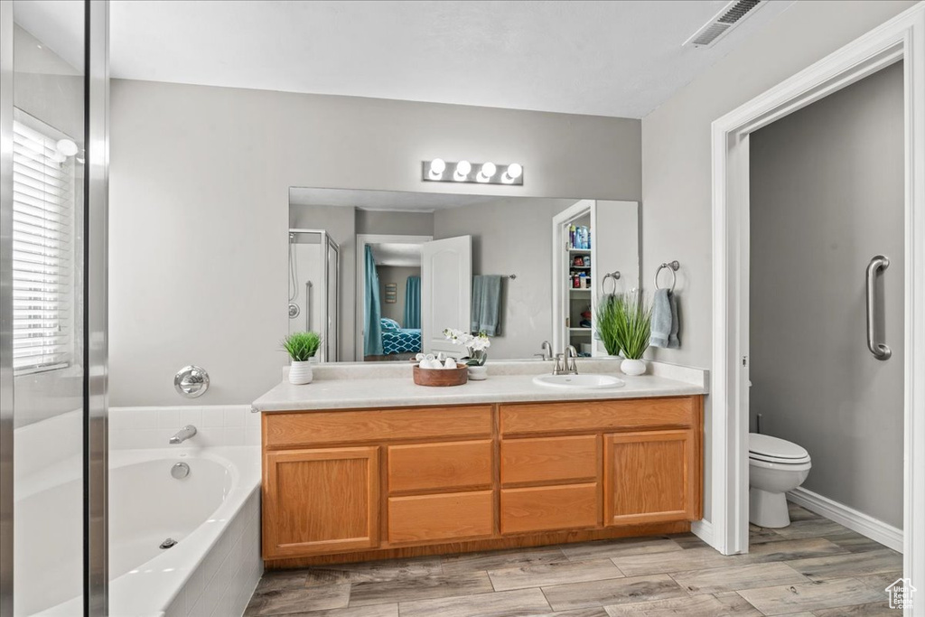 Full bath with vanity, a garden tub, a stall shower, and wood finished floors