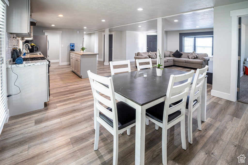 Dining area with recessed lighting and light wood-type flooring