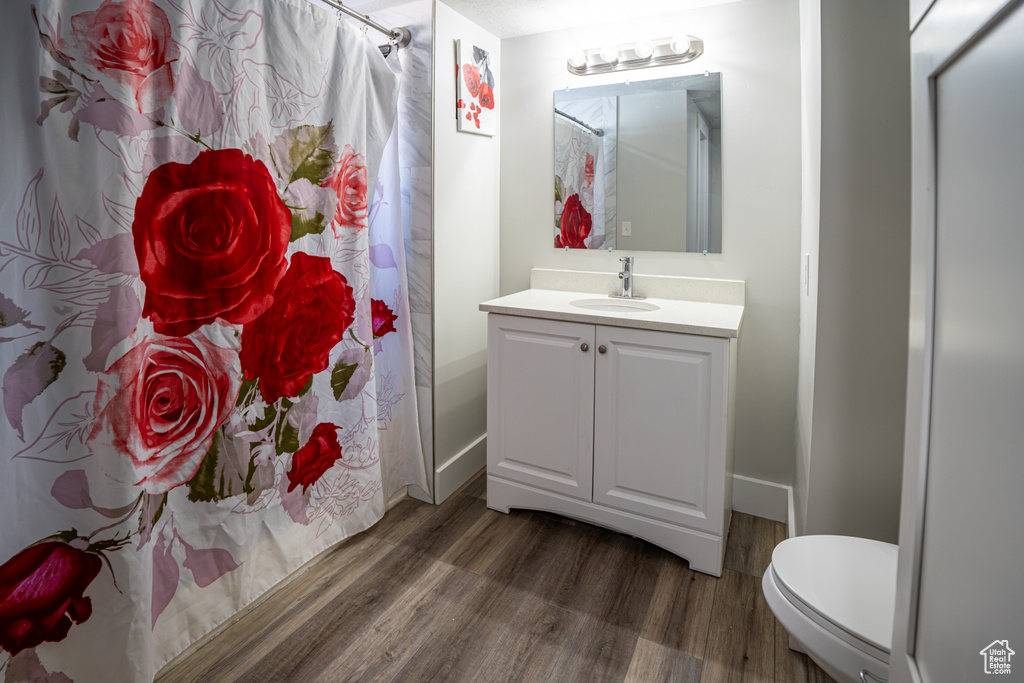 Full bath with wood finished floors, vanity, and shower / bathtub combination with curtain