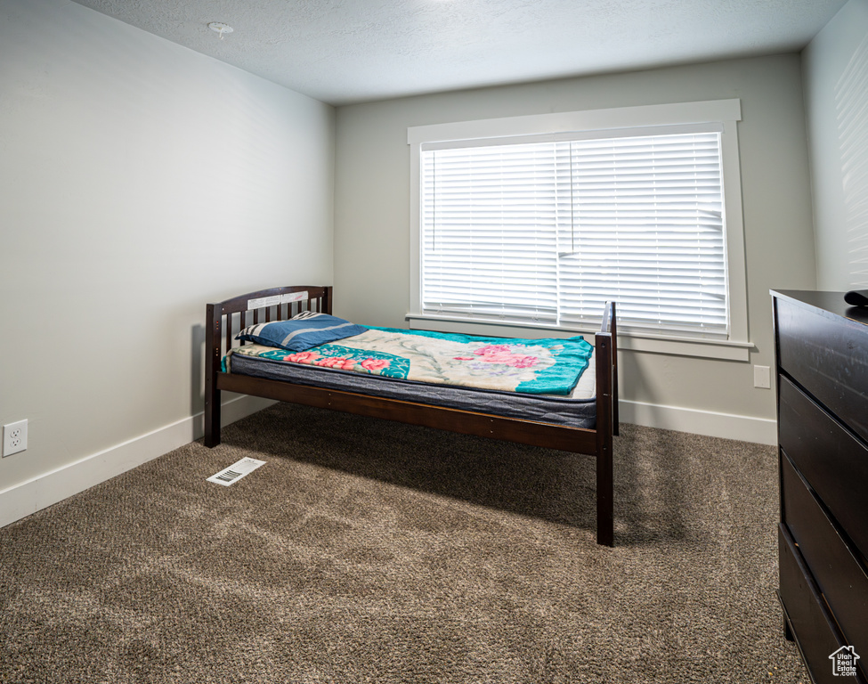 Carpeted bedroom with baseboards and a textured ceiling