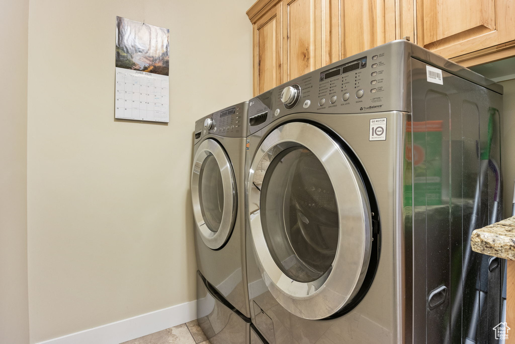 Laundry room with washing machine and clothes dryer, cabinet space, and light tile patterned flooring