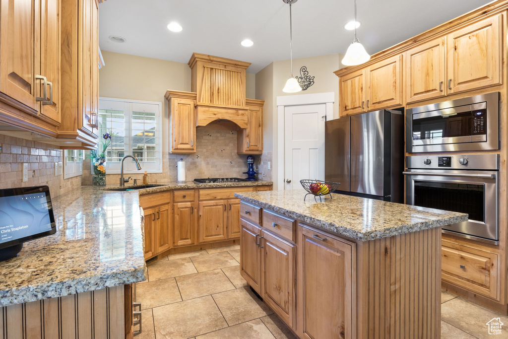 Kitchen featuring stainless steel appliances, premium range hood, backsplash, and light stone counters