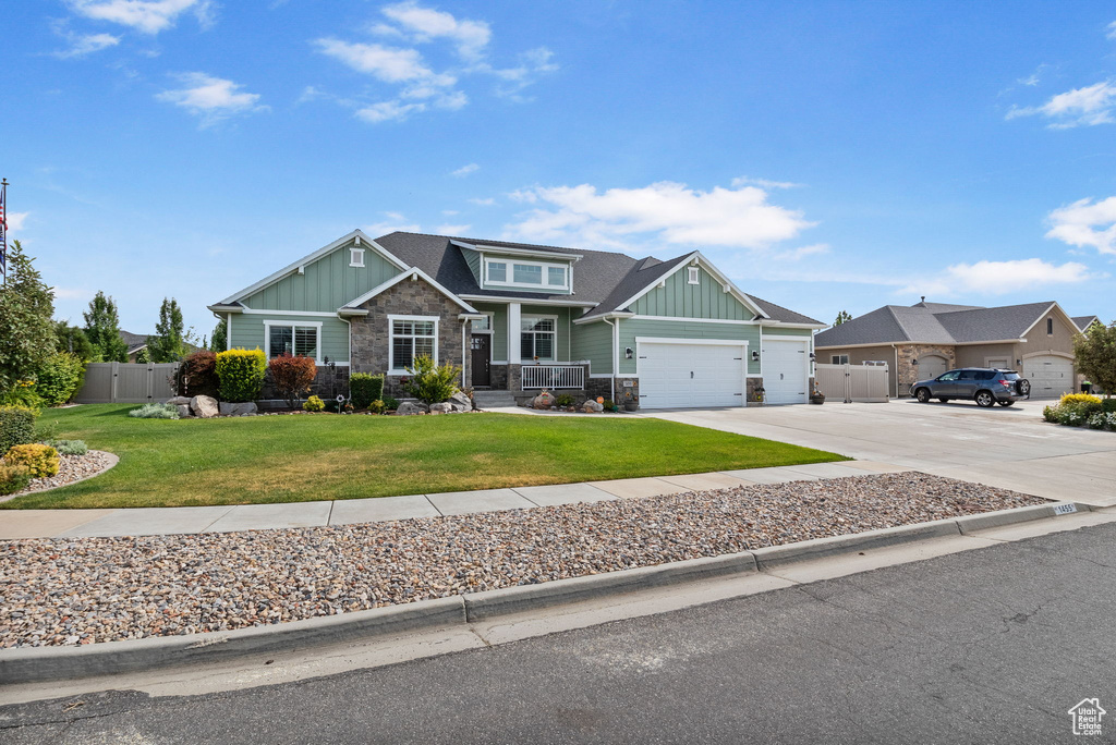 Craftsman-style home featuring board and batten siding, stone siding, an attached garage, and concrete driveway