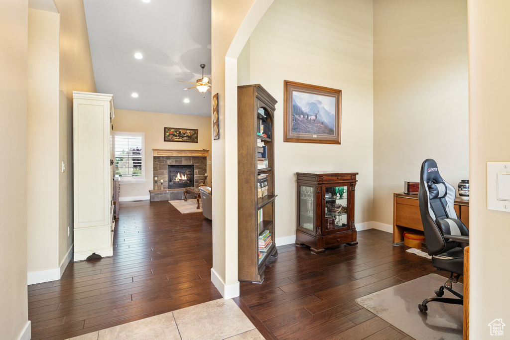 Office featuring a fireplace, dark wood-type flooring, a ceiling fan, arched walkways, and recessed lighting