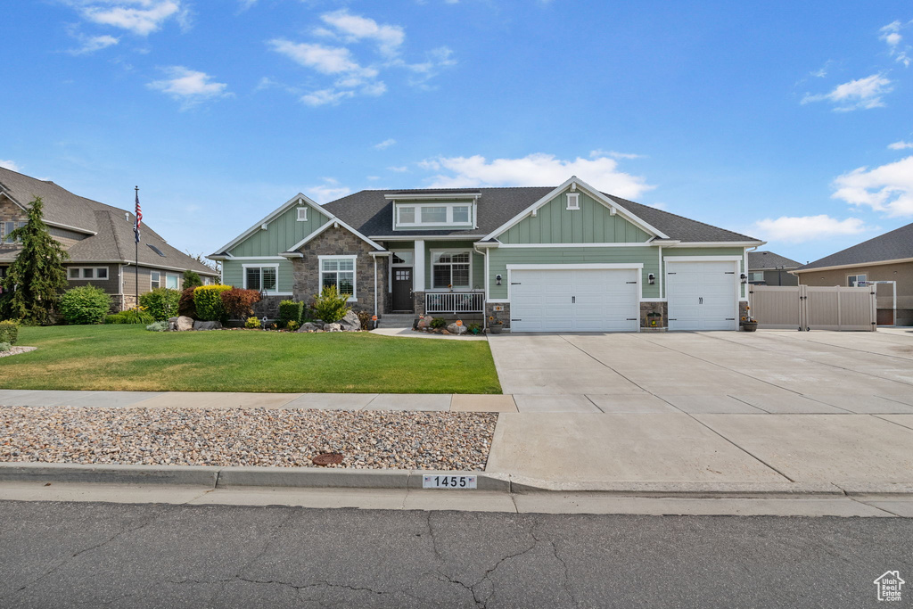 Craftsman-style home with board and batten siding, a garage, concrete driveway, and stone siding