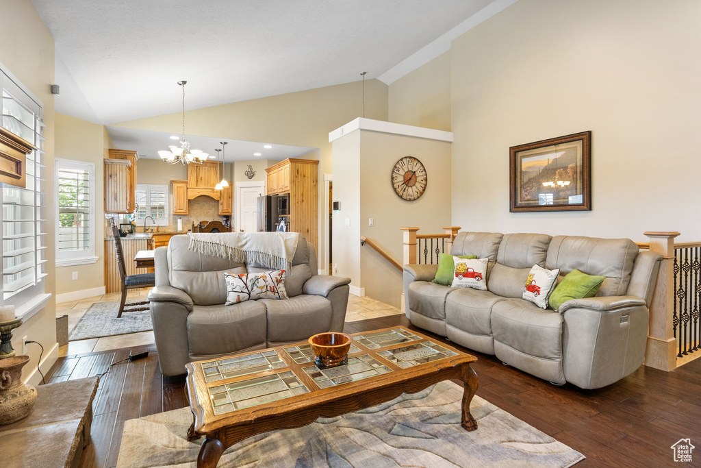 Living room featuring a chandelier, dark wood-style flooring, and high vaulted ceiling