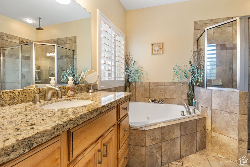 Bathroom featuring a stall shower, vanity, a jetted tub, and tile patterned floors