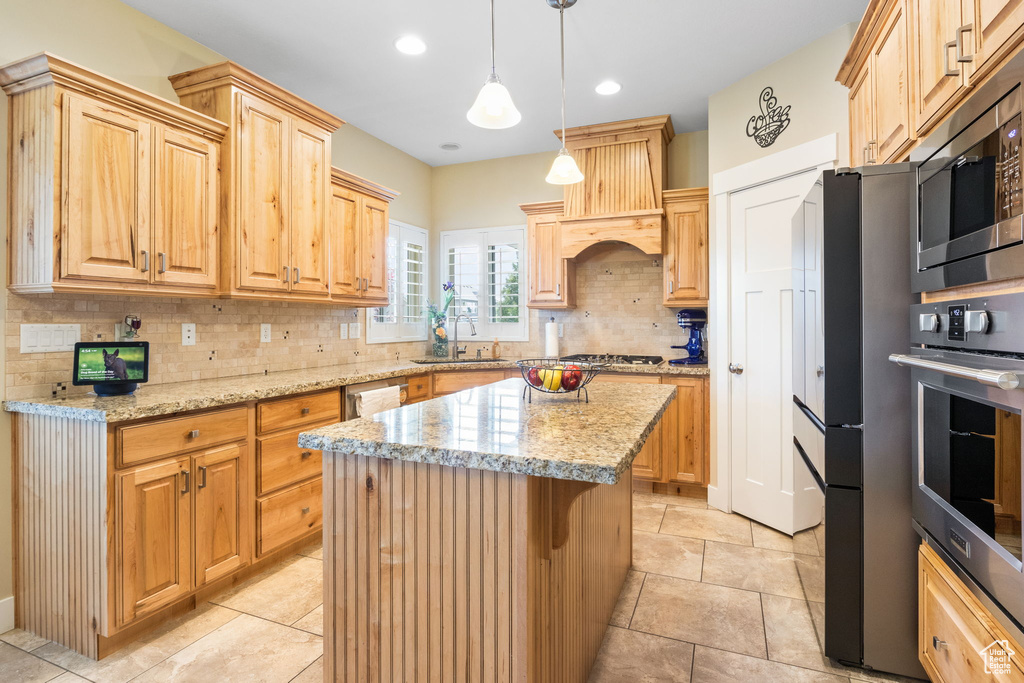 Kitchen featuring stainless steel appliances, premium range hood, tasteful backsplash, a kitchen island, and light stone countertops