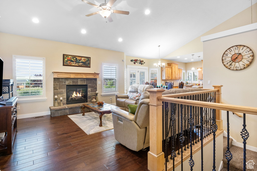 Living area featuring lofted ceiling, a ceiling fan, a fireplace, plenty of natural light, and dark wood finished floors
