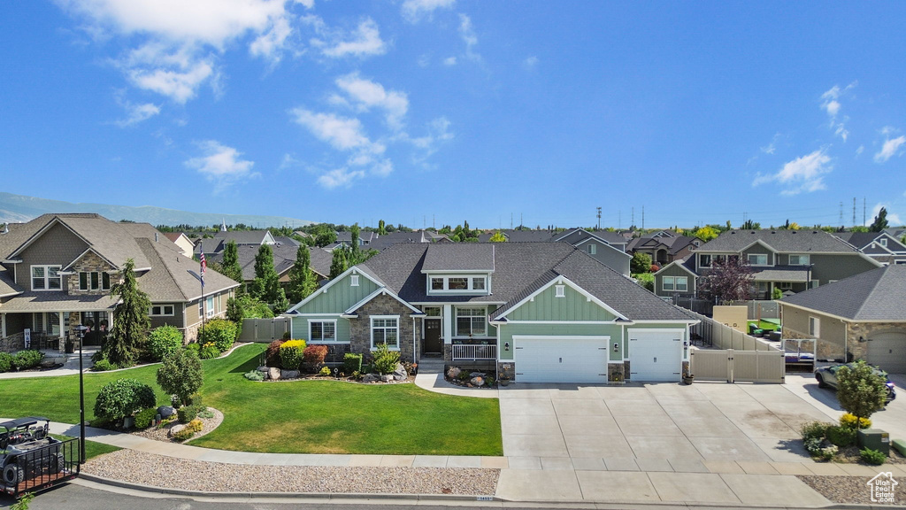 Craftsman-style house with board and batten siding, a residential view, driveway, an attached garage, and stone siding