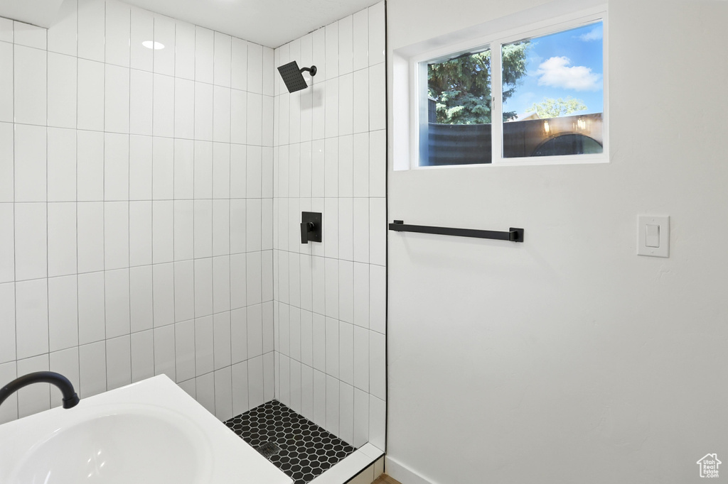 Bathroom featuring a tile shower and a sink