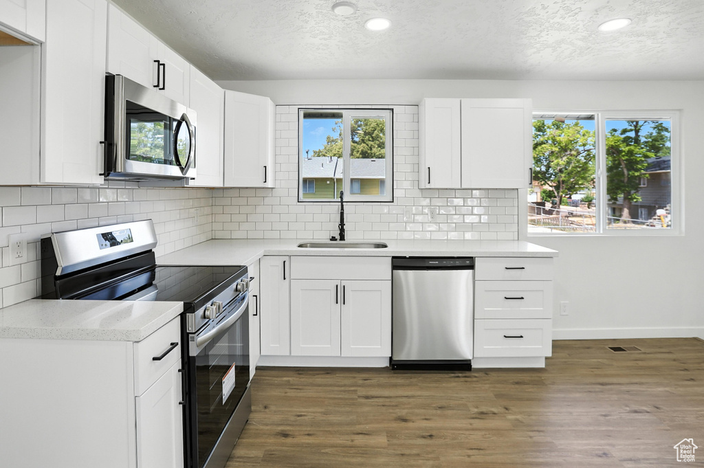 Kitchen with stainless steel appliances, a textured ceiling, healthy amount of natural light, backsplash, and recessed lighting