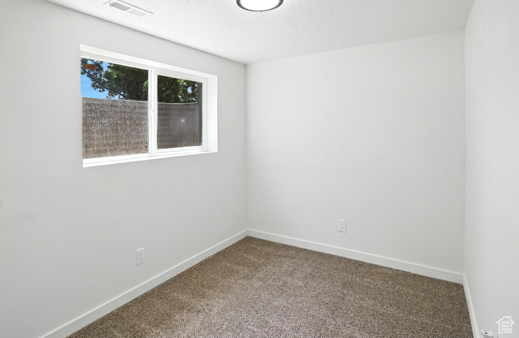 Empty room featuring dark colored carpet and baseboards