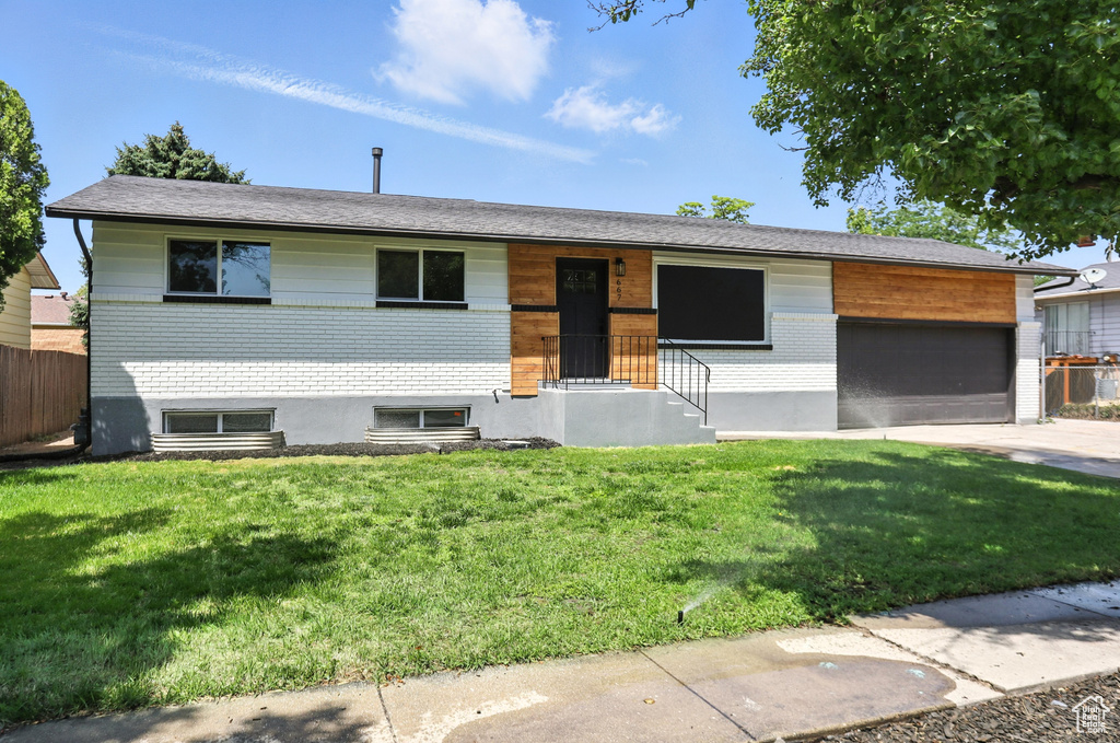 View of front of home featuring an attached garage, concrete driveway, and brick siding