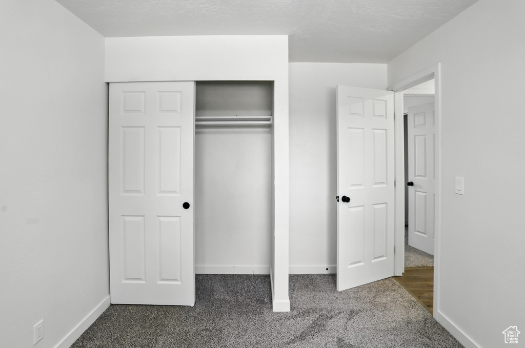Unfurnished bedroom with dark carpet and a closet