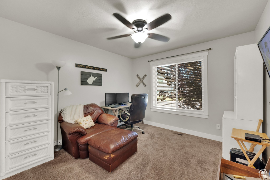 Carpeted office space featuring ceiling fan and baseboards