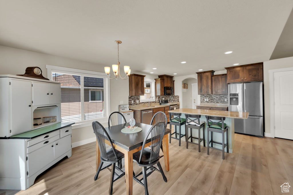Dining area featuring arched walkways, light wood-style flooring, a chandelier, and recessed lighting