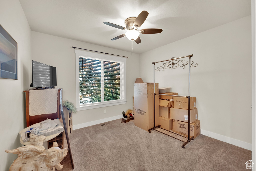 Carpeted office space featuring a ceiling fan and baseboards