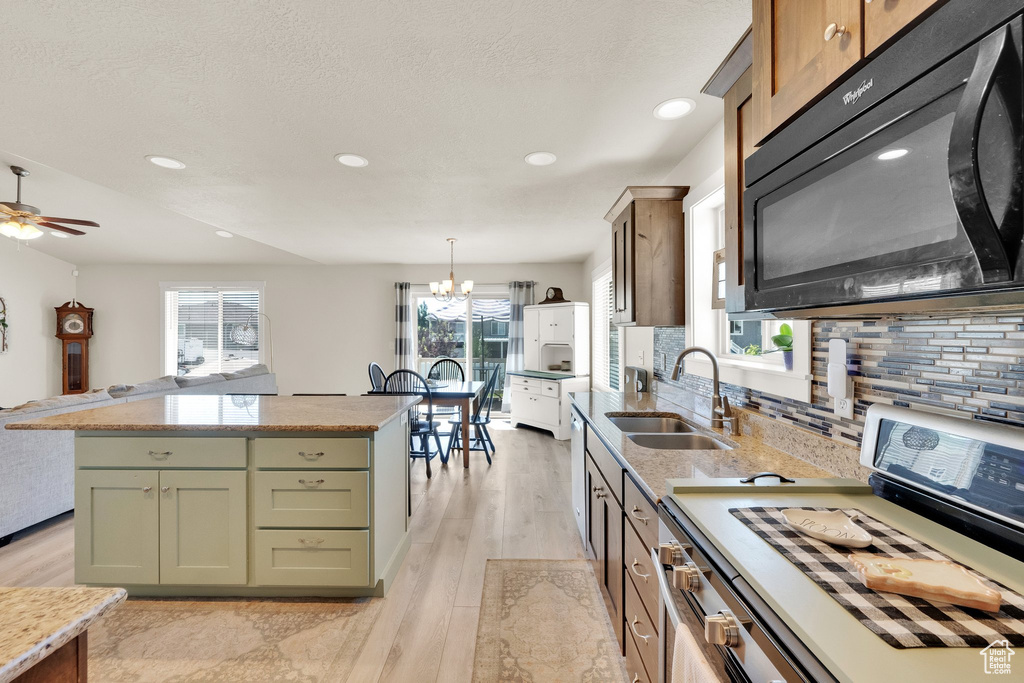 Kitchen with black microwave, white range, backsplash, recessed lighting, and light wood-style flooring