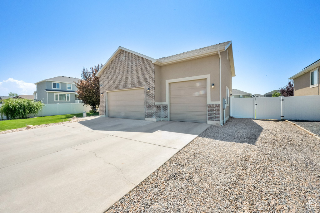 View of front of house featuring a garage, a gate, driveway, and brick siding