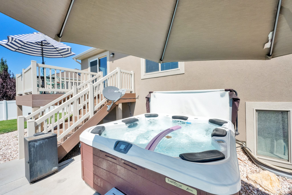View of patio / terrace featuring a hot tub, a wooden deck, and stairs