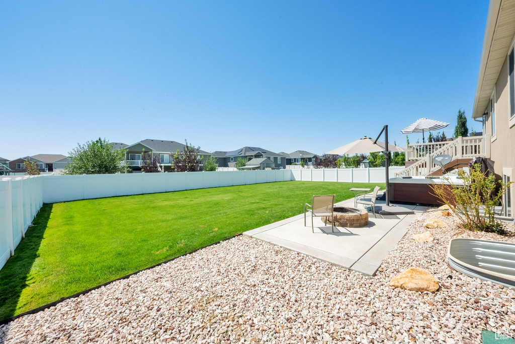 Fenced backyard with a patio area, a fire pit, a residential view, and a hot tub