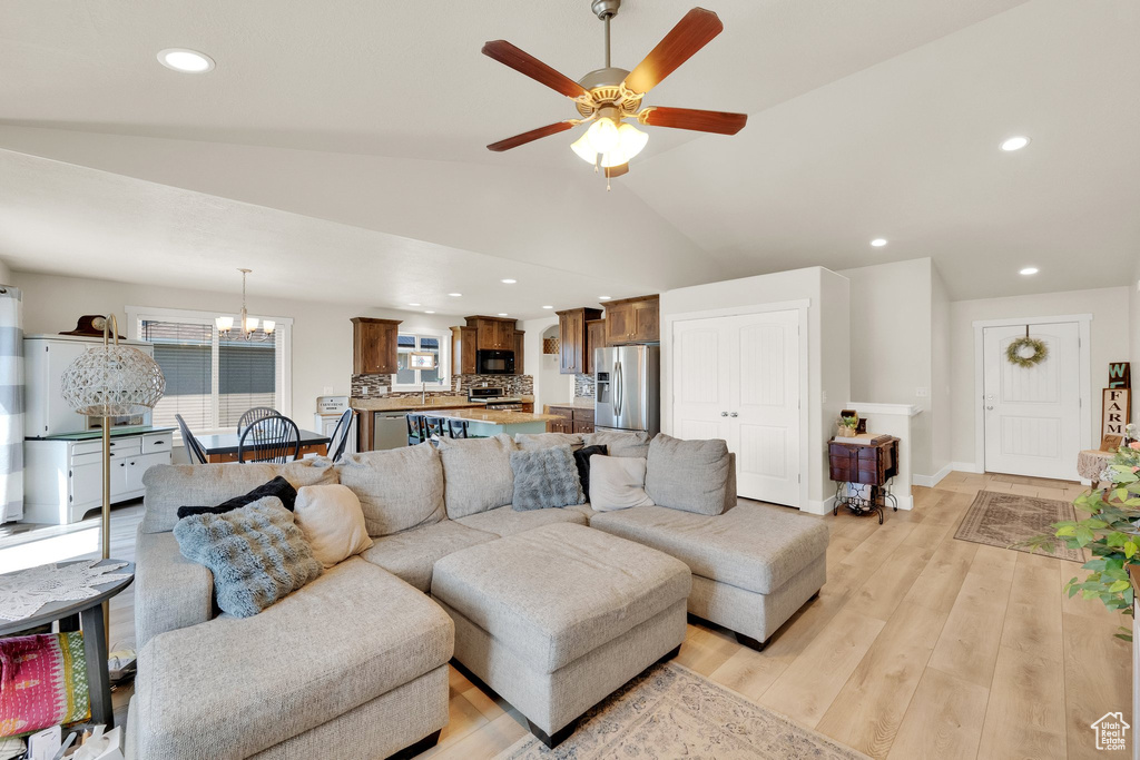 Living room featuring a chandelier, light wood-style floors, ceiling fan, vaulted ceiling, and recessed lighting