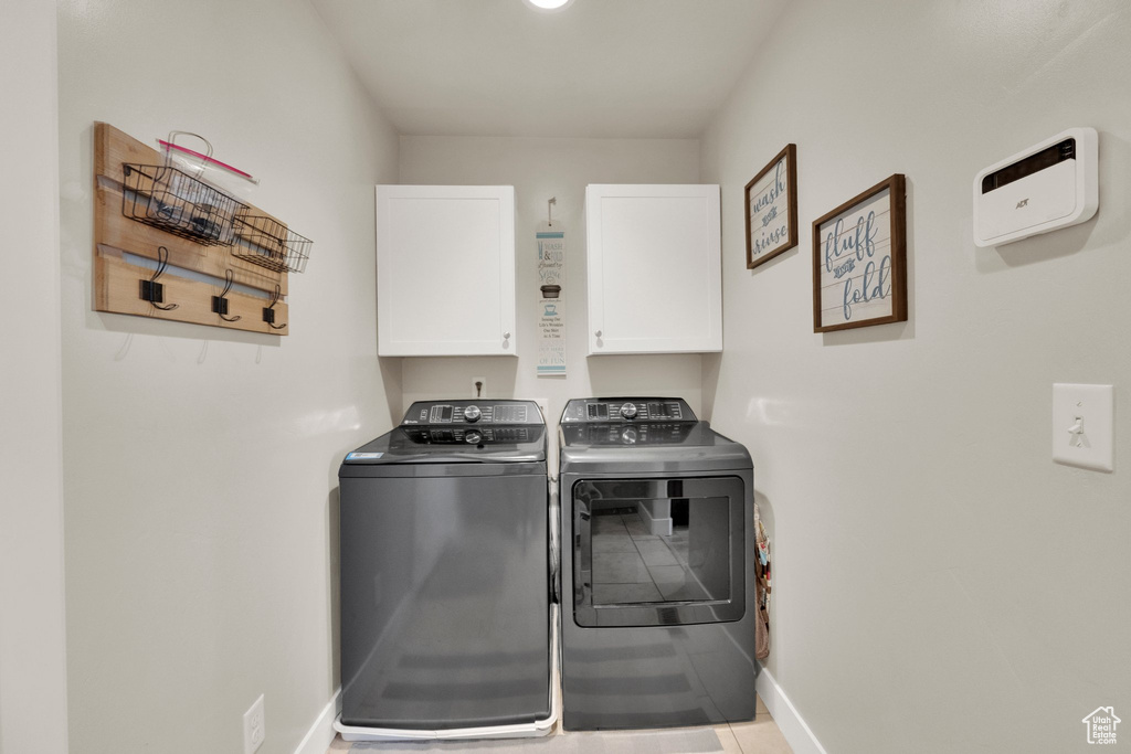 Washroom with cabinet space, separate washer and dryer, and tile patterned floors