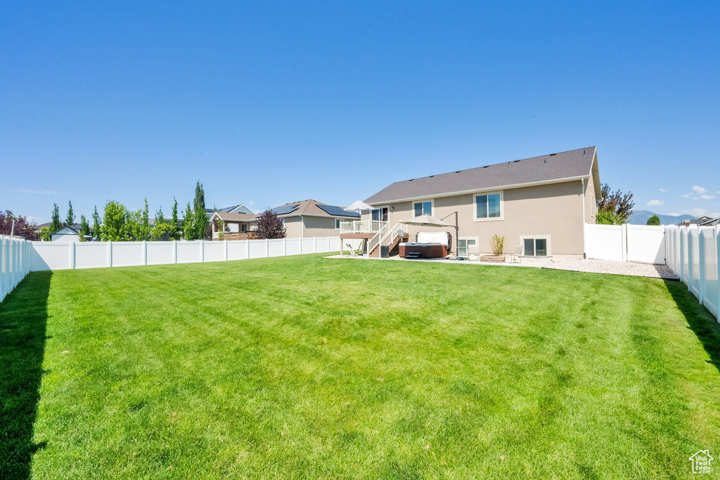 Back of house featuring a fenced backyard, stucco siding, and stairs