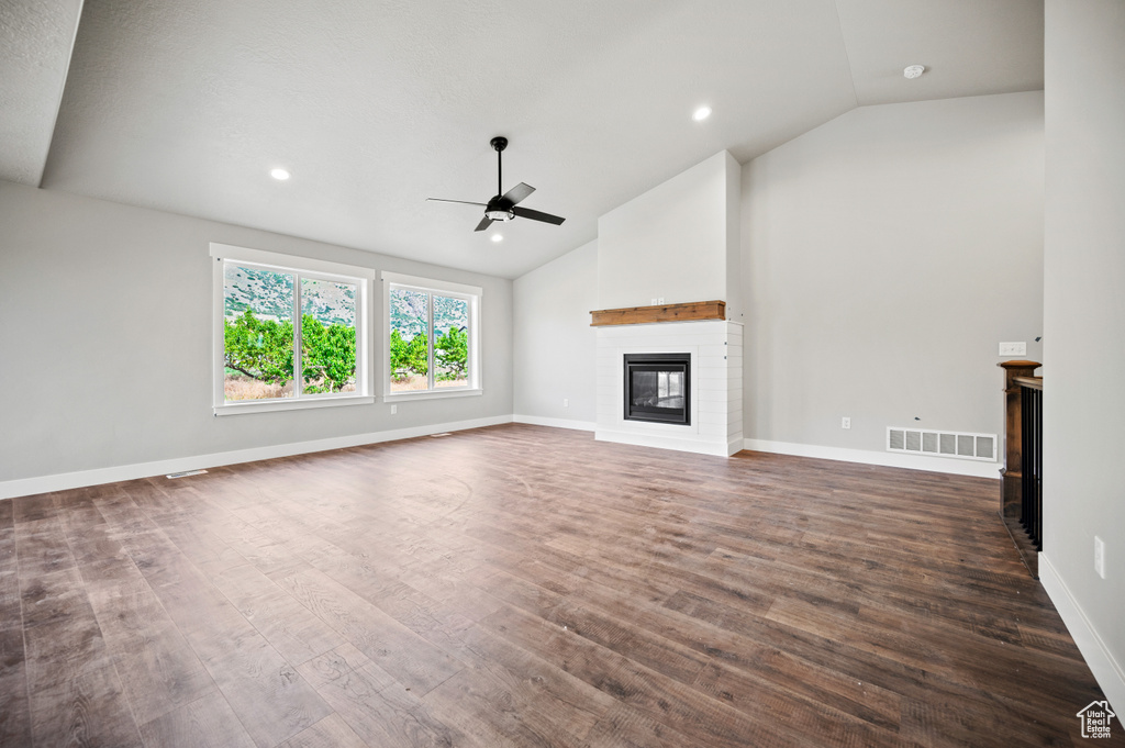 Unfurnished living room featuring a glass covered fireplace, ceiling fan, dark wood-style flooring, recessed lighting, and high vaulted ceiling