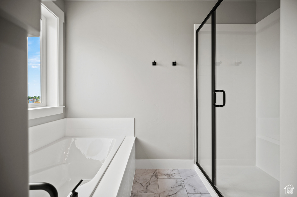 Full bathroom featuring marble look tile flooring, a shower stall, and a garden tub