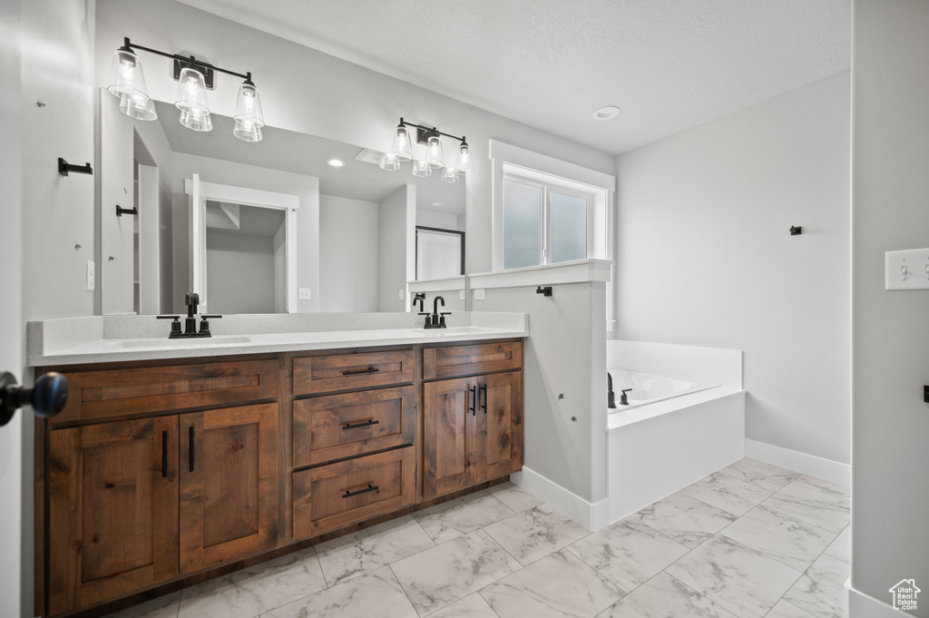 Full bath featuring marble look tile flooring, double vanity, and a bath