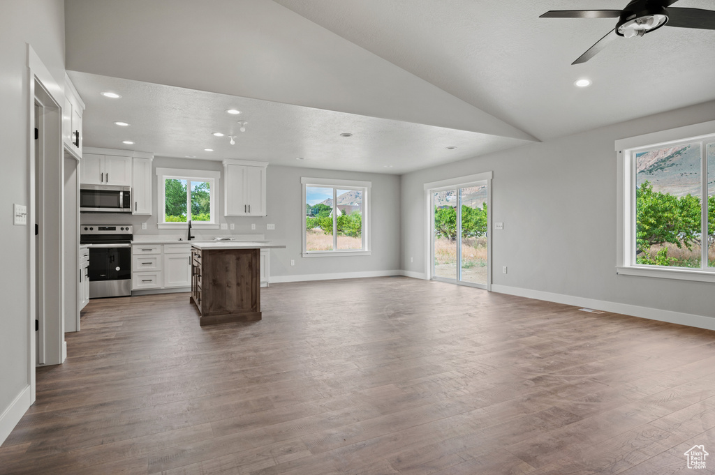 Unfurnished living room with lofted ceiling, plenty of natural light, dark wood finished floors, and recessed lighting