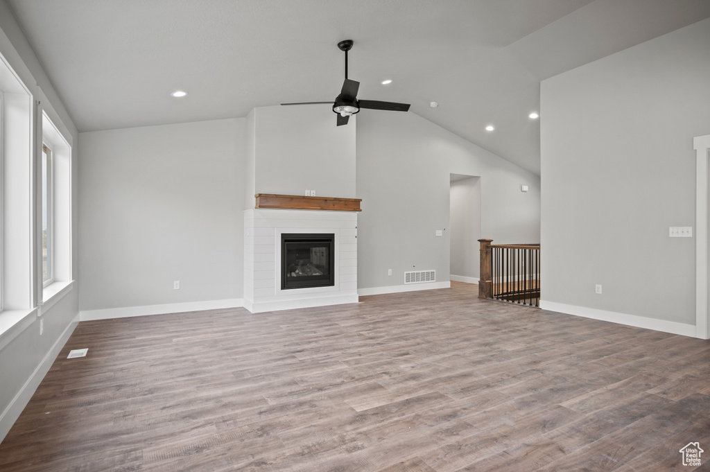 Unfurnished living room featuring a ceiling fan, lofted ceiling, recessed lighting, wood finished floors, and a glass covered fireplace