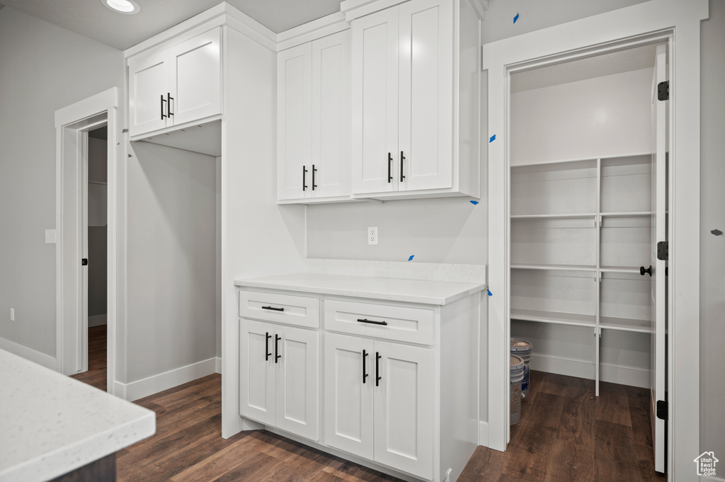 Kitchen featuring dark wood-type flooring, white cabinets, recessed lighting, and light stone countertops